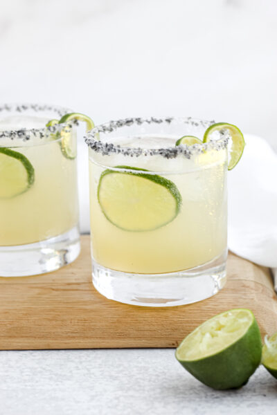 Two Easy Skinny Margaritas with salted rims sitting on a wooden tray