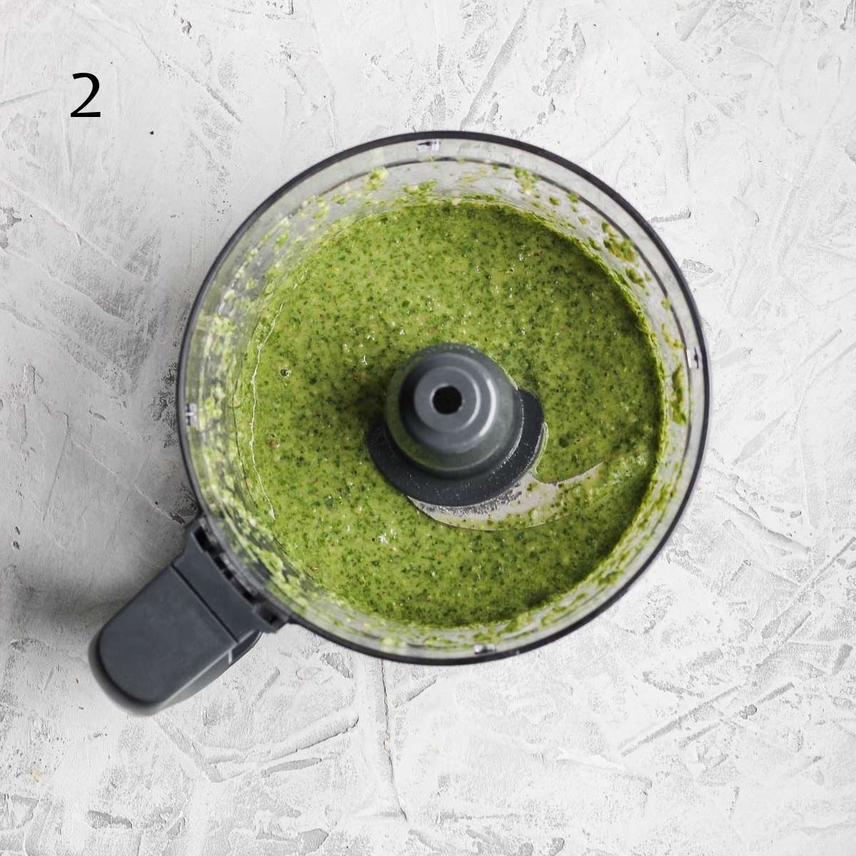 a food processor with blended dairy free pesto inside