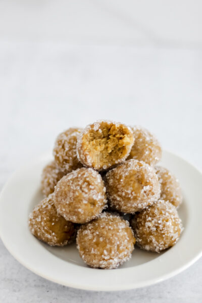 Lemon Cake Protein Balls stacked on top of each other and the top ball has a bit taken out of it