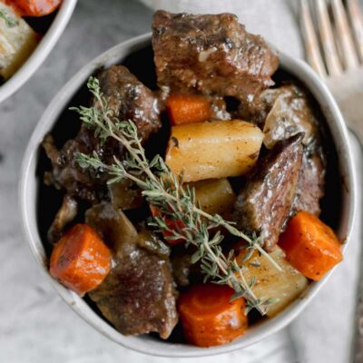 A bowl filled with Whole30 pot roast and topped with two sprigs of fresh thyme.