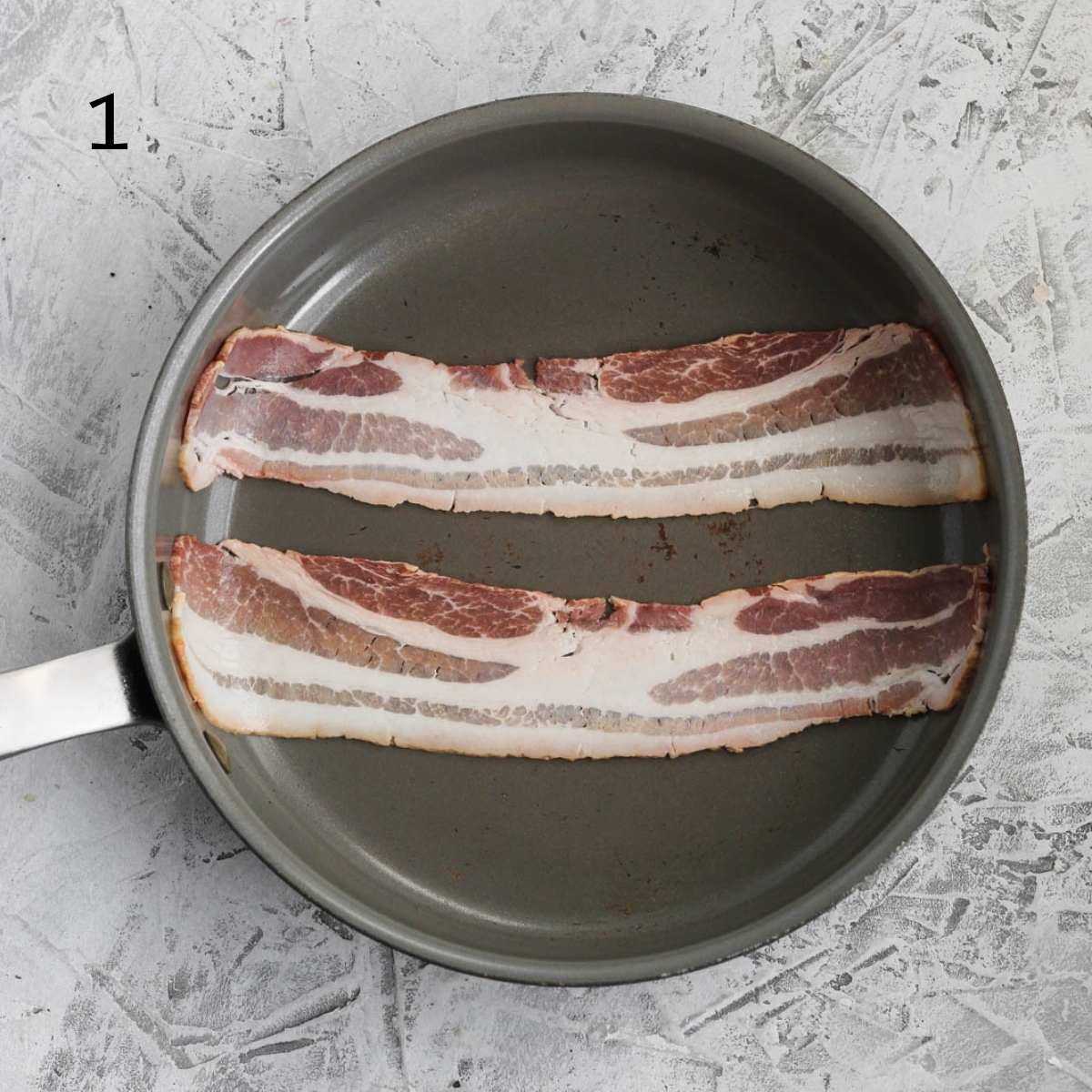 a pan with two strips of uncooked bacon inside