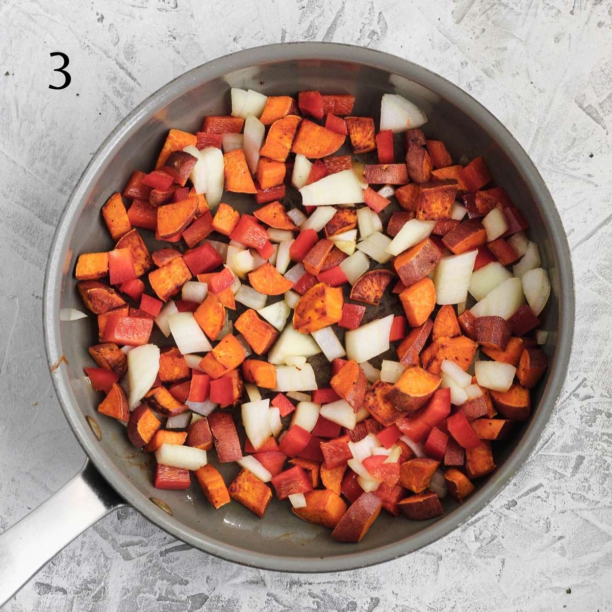 a pan with diced sweet potatoes, diced onion, and diced red bell peppers inside
