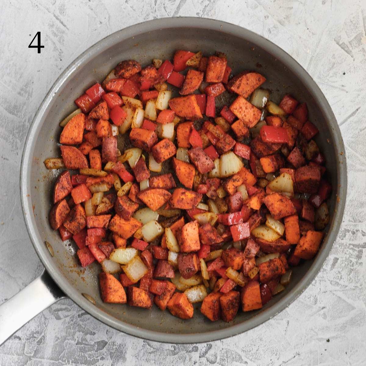 cooked diced sweet potatoes, diced onions, diced red bell peppers, and seasonings inside a pan