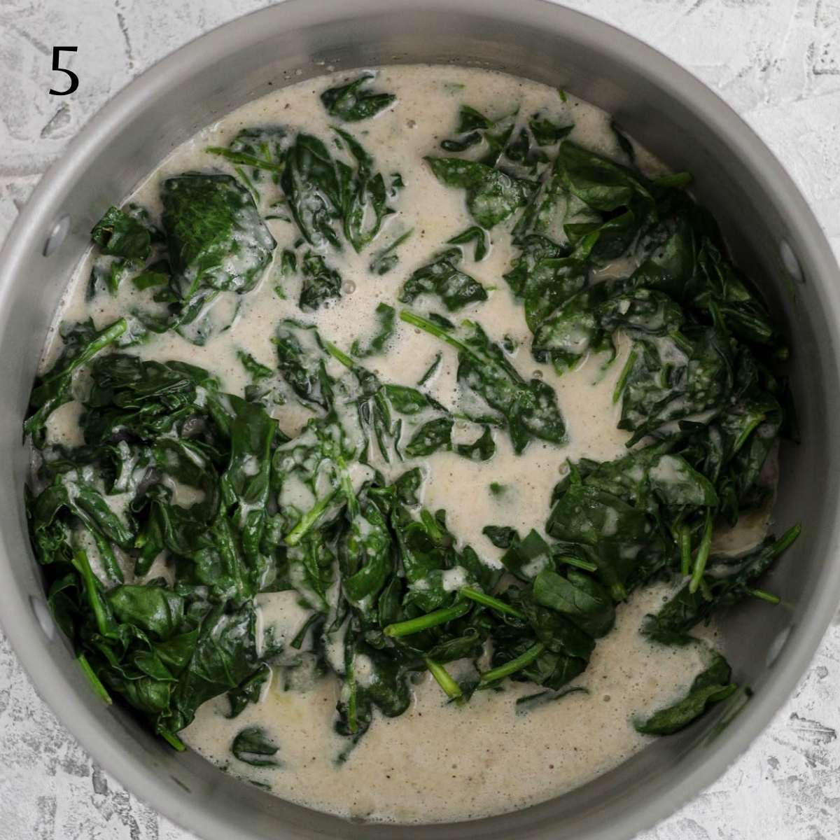 a big pot with sautéd spinach and dairy free cream