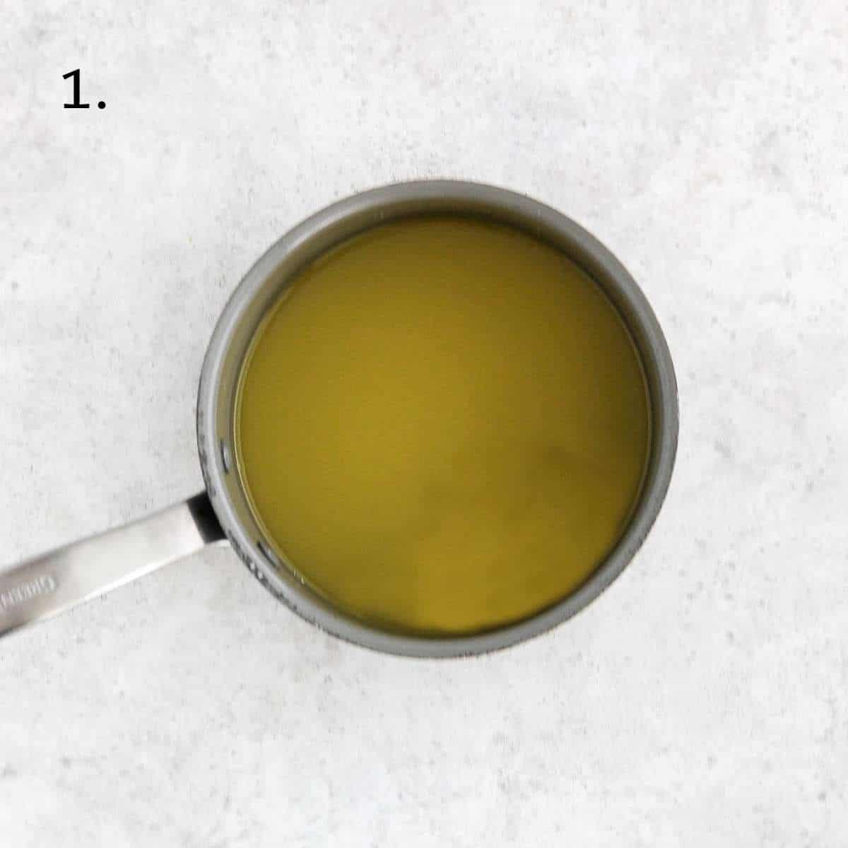 A sauce pan filled with orange juice and honey.