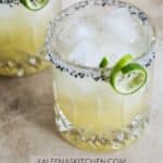 A Pinterest pin poster with two glasses of topo chico margaritas with curly lime twists on the side of a a cocktail glass rimmed with white and black salt.