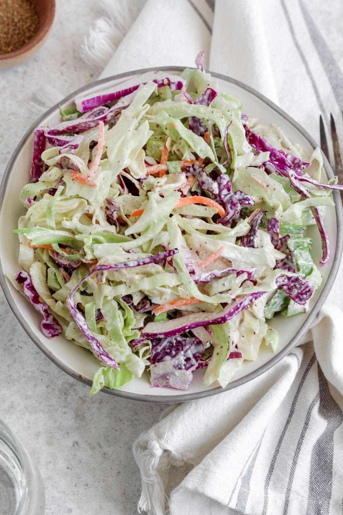 A bowl filled with dairy free coleslaw sitting on a tea towel.