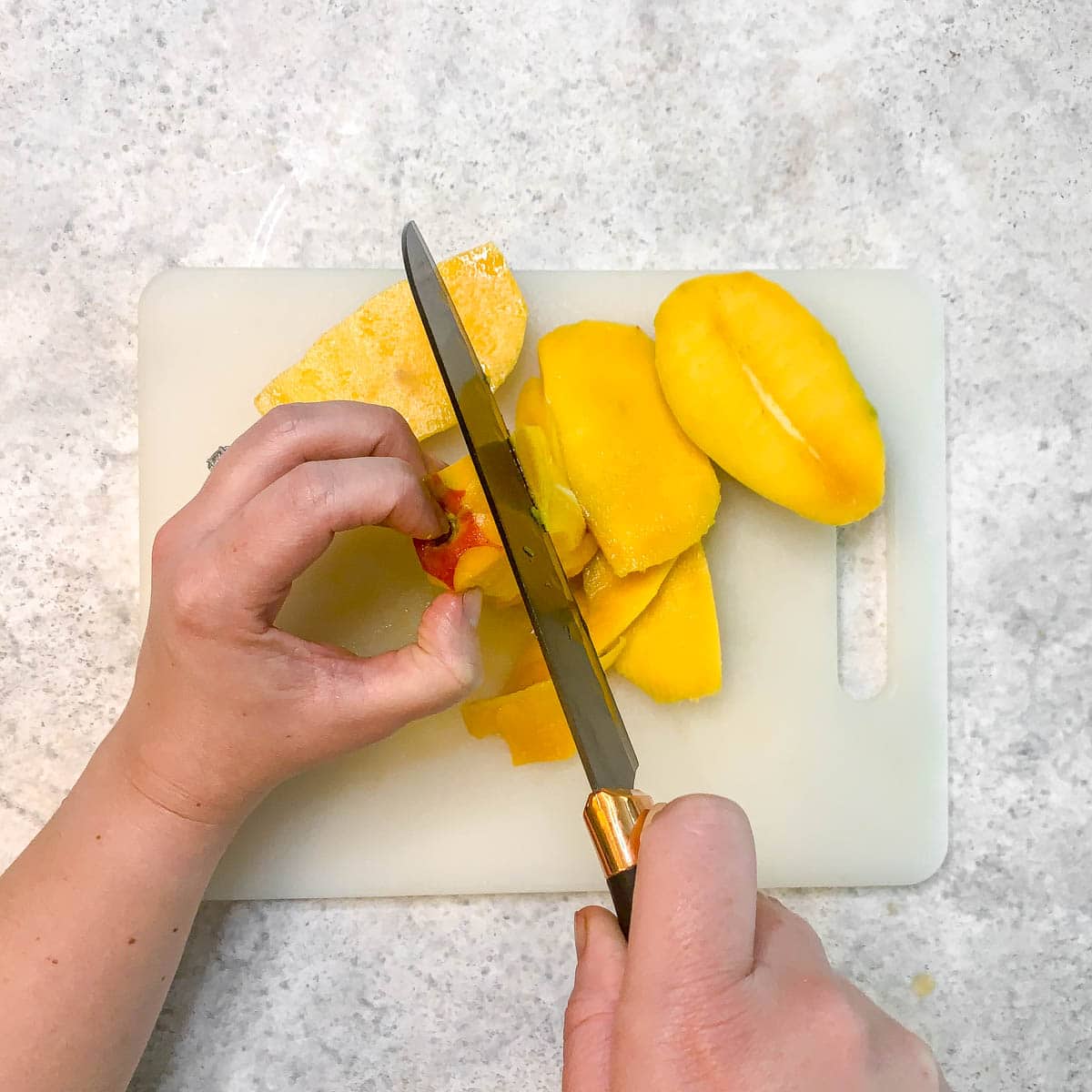 Hands cutting a mango.