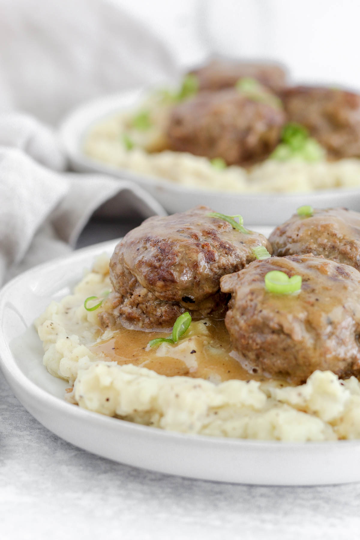 A plate filled with mashed potatoes and Swedish meatballs and gravy on top.