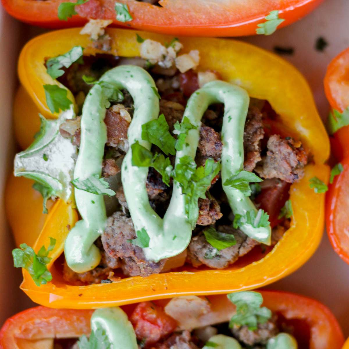A stuffed pepper topped with avocado crema and cilantro.