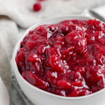A white bowl filled with cranberry orange sauce sitting on a tan tea towel.