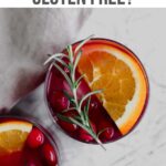 Is Deep Eddy Vodka Gluten Free Pinterest Poster with a top view of a cocktail glass filled with cranberry sangria and topped with fresh cranberries, an orange slice, and a fresh sprig of rosemary.