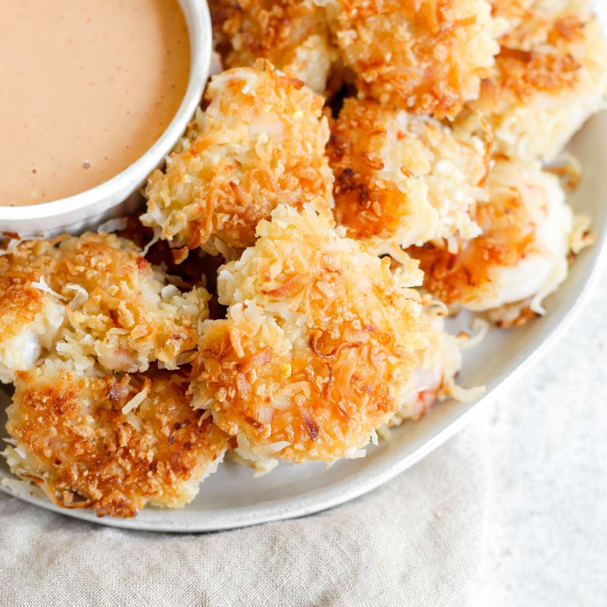 Gluten free coconut shrimp on a plate with a side of bang band sauce.