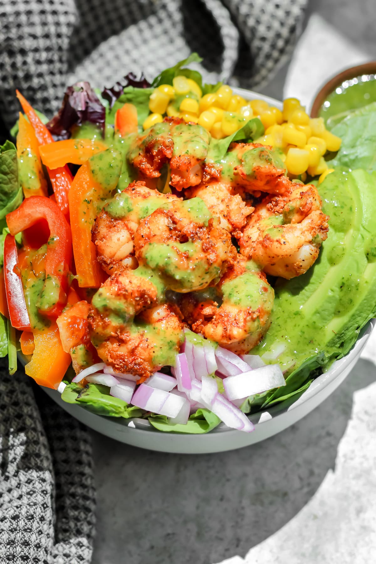 Blackened Shrimp Salad with Cilantro Lime dressing in a bowl with a black tea towel off to the side.