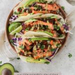 A Pinterest pin poster with a plate filled with three air fryer salmon tacos and two lime wedges sitting on the plate.