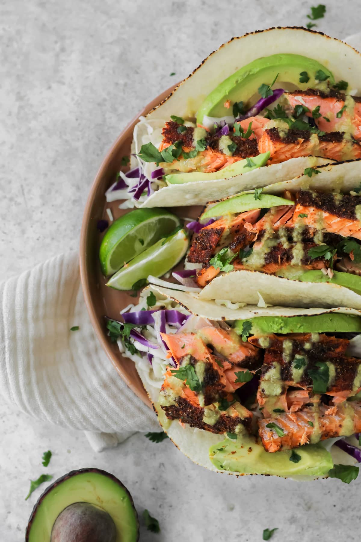 A plate filled with three air fryer salmon tacos and two lime wedges sitting on the plate.