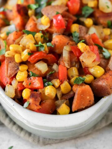 A bowl of sweet potato succotash sitting on a tea towel.