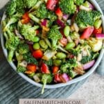 A Pinterest pin poster with a bowl filled with broccoli and edamame salad sitting on an blue tea towel.
