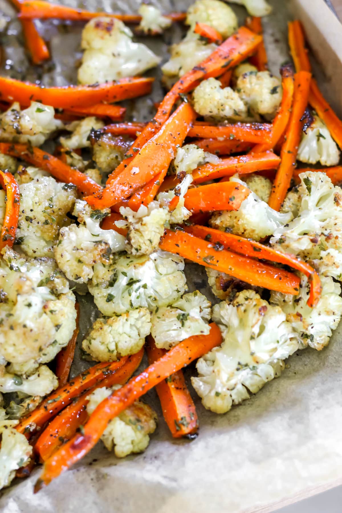 A sheet pan filled with hot honey roasted carrots and cauliflower.