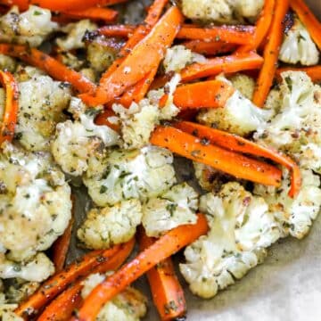 A sheet pan filled with hot honey roasted carrots and cauliflower.