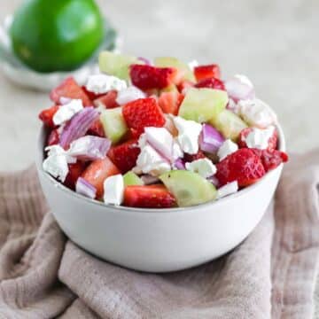 A bowl filled with strawberry cucumber salad.