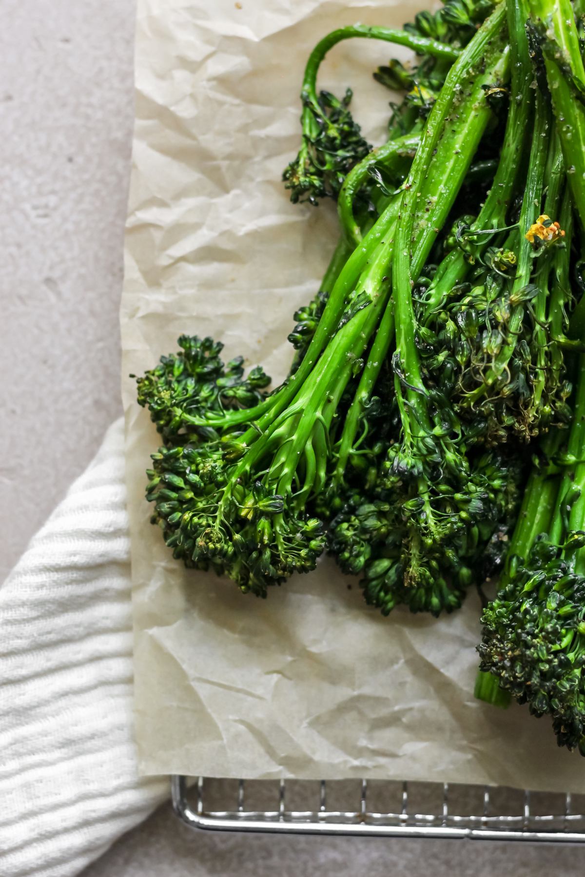 Air fryer broccolini sitting on tan parchment paper.
