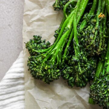 Air fryer broccolini sitting on tan parchment paper.