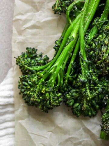 Air fryer broccolini sitting on tan parchment paper.
