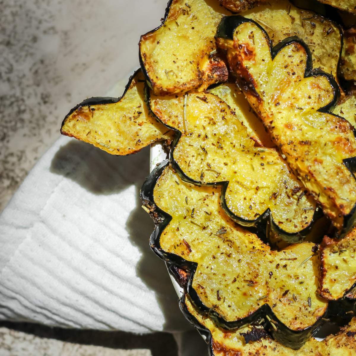 Air fryer acorn squash sitting in a white oval serving dish with a white tea towel underneath.