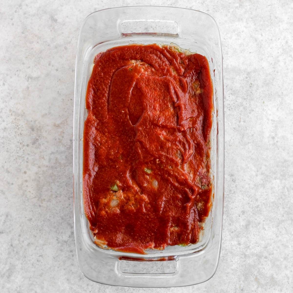 A meatloaf pan filled with whole30 meatloaf topped with ketchup.