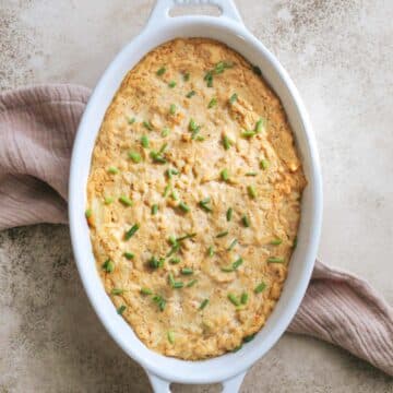 A white oval serving dish filled with dairy free crab dip sitting on a tea towel.