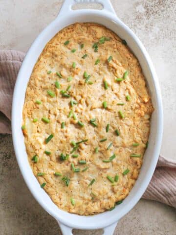 A white oval serving dish filled with dairy free crab dip sitting on a tea towel.