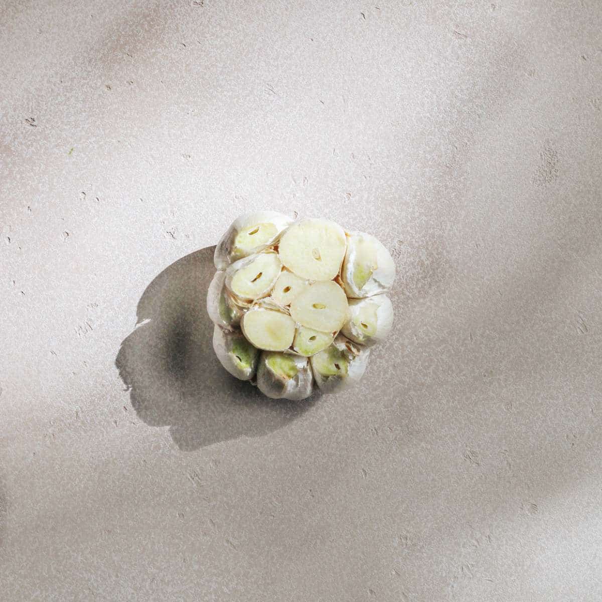 A head of garlic with the top cut off.