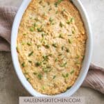 A Pinterest pin with a white oval serving dish filled with dairy free crab dip sitting on a tea towel.