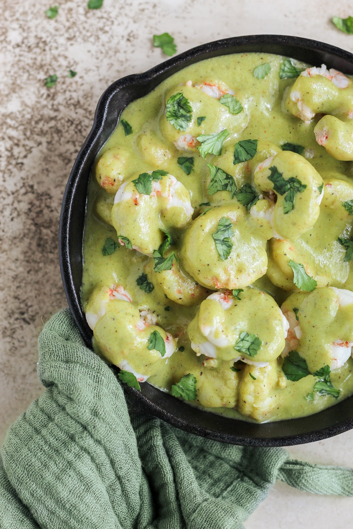 Creamy poblano shrimp in a cast iron skillet with cilantro sprinkled on top.