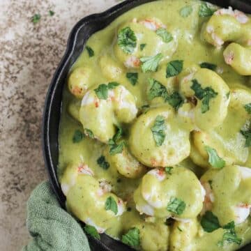 Creamy poblano shrimp in a cast iron skillet with cilantro sprinkled on top.