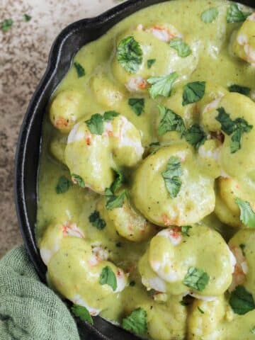 Creamy poblano shrimp in a cast iron skillet with cilantro sprinkled on top.