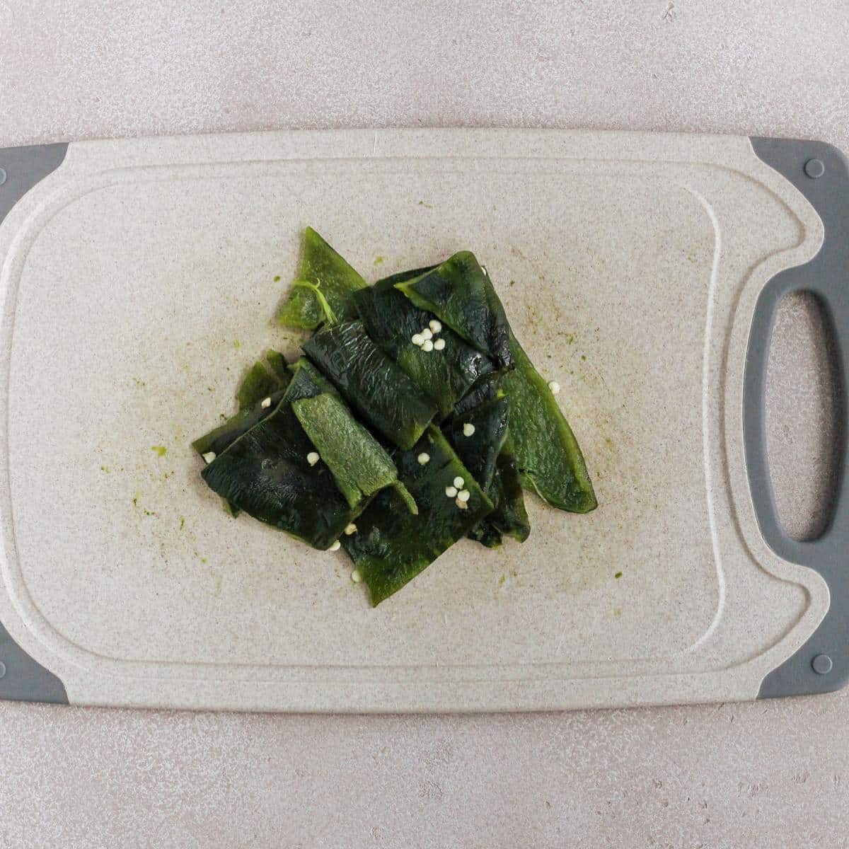 Roasted poblano peppers cut into chunks on a cutting board.
