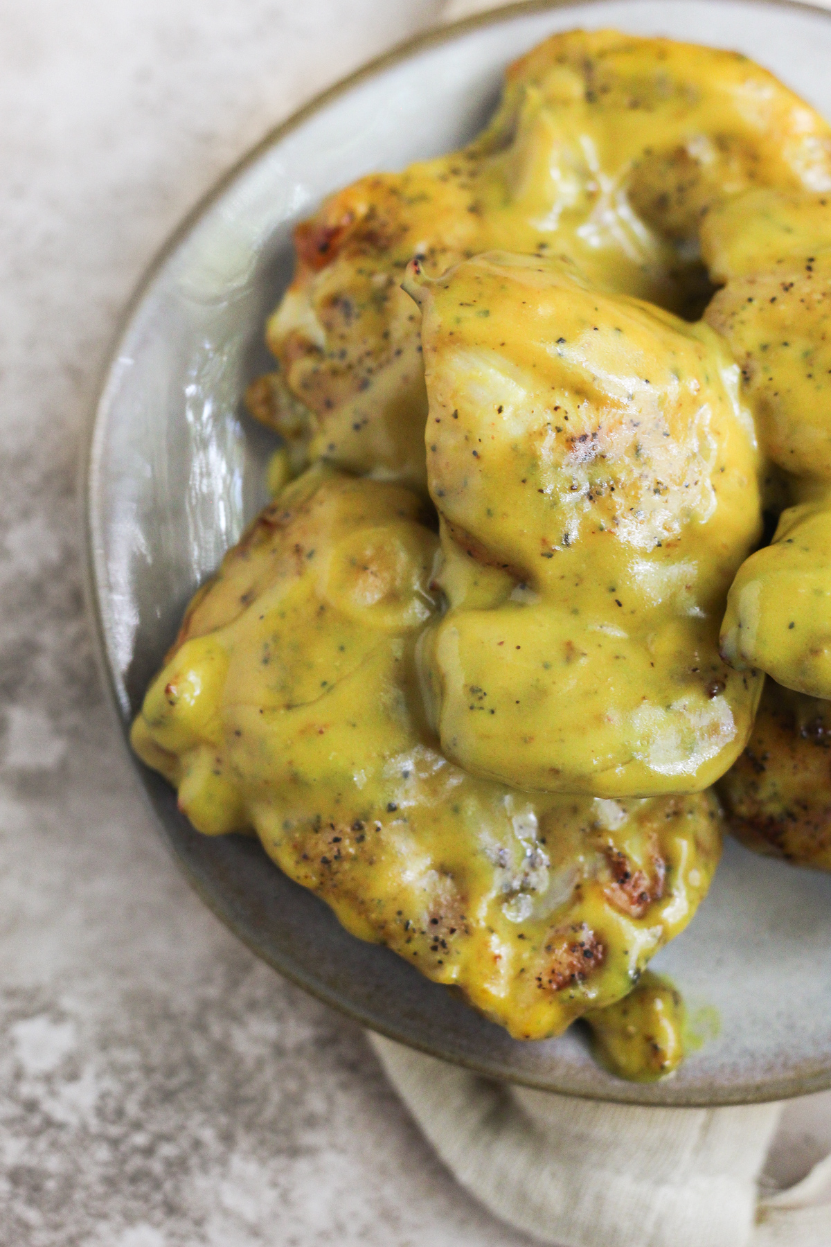 Honey mustard chicken thighs stacked on a plate.
