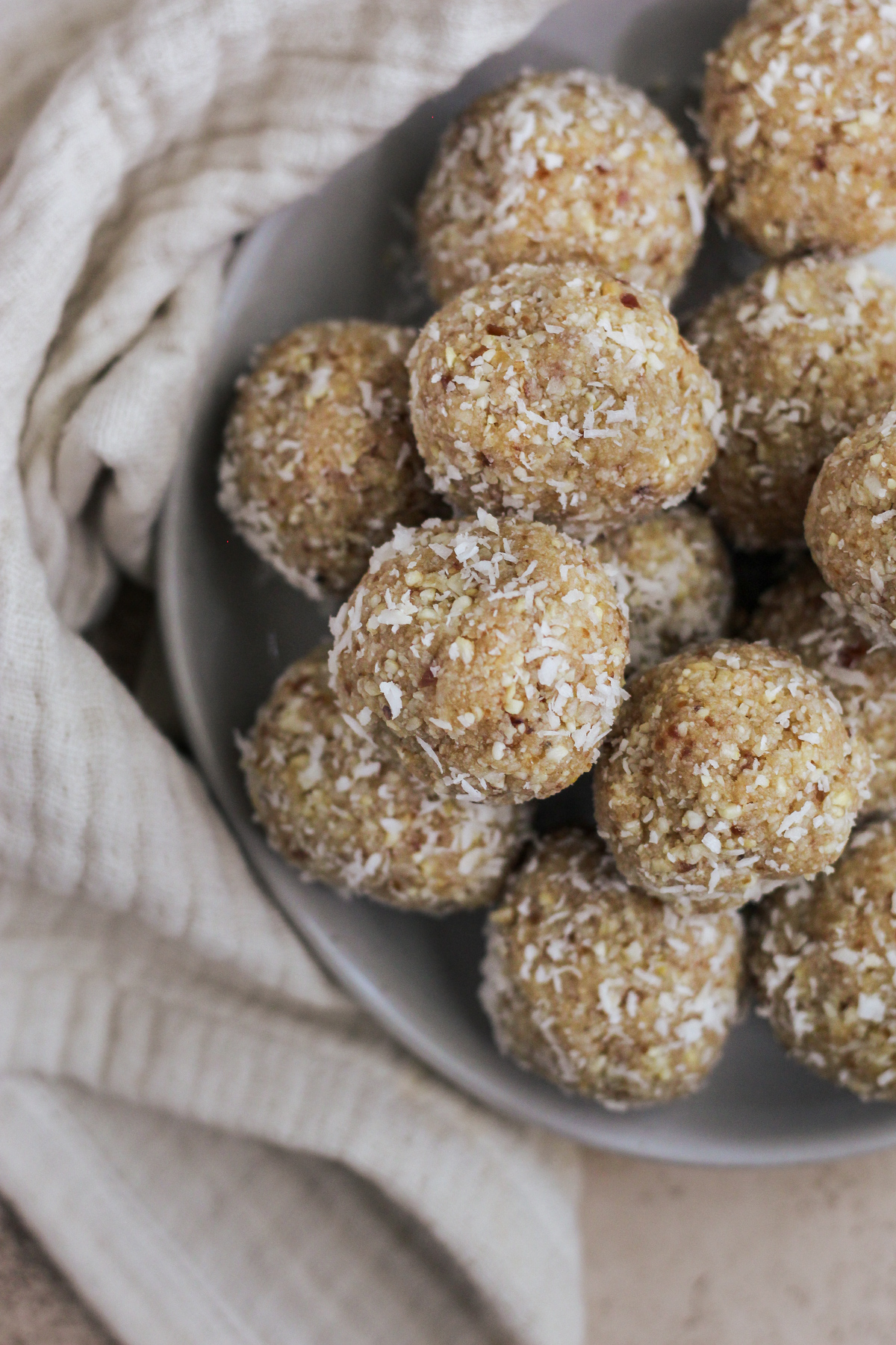 A plated with lemon date coconut balls stacked on top of each other.