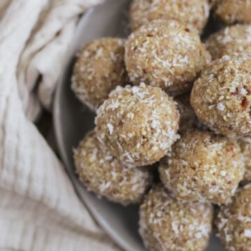A plated with lemon date coconut balls stacked on top of each other.