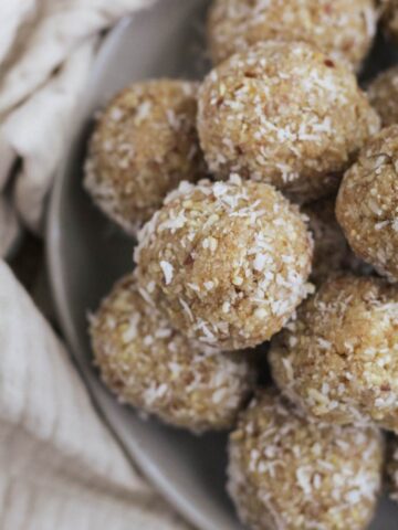 A plated with lemon date coconut balls stacked on top of each other.