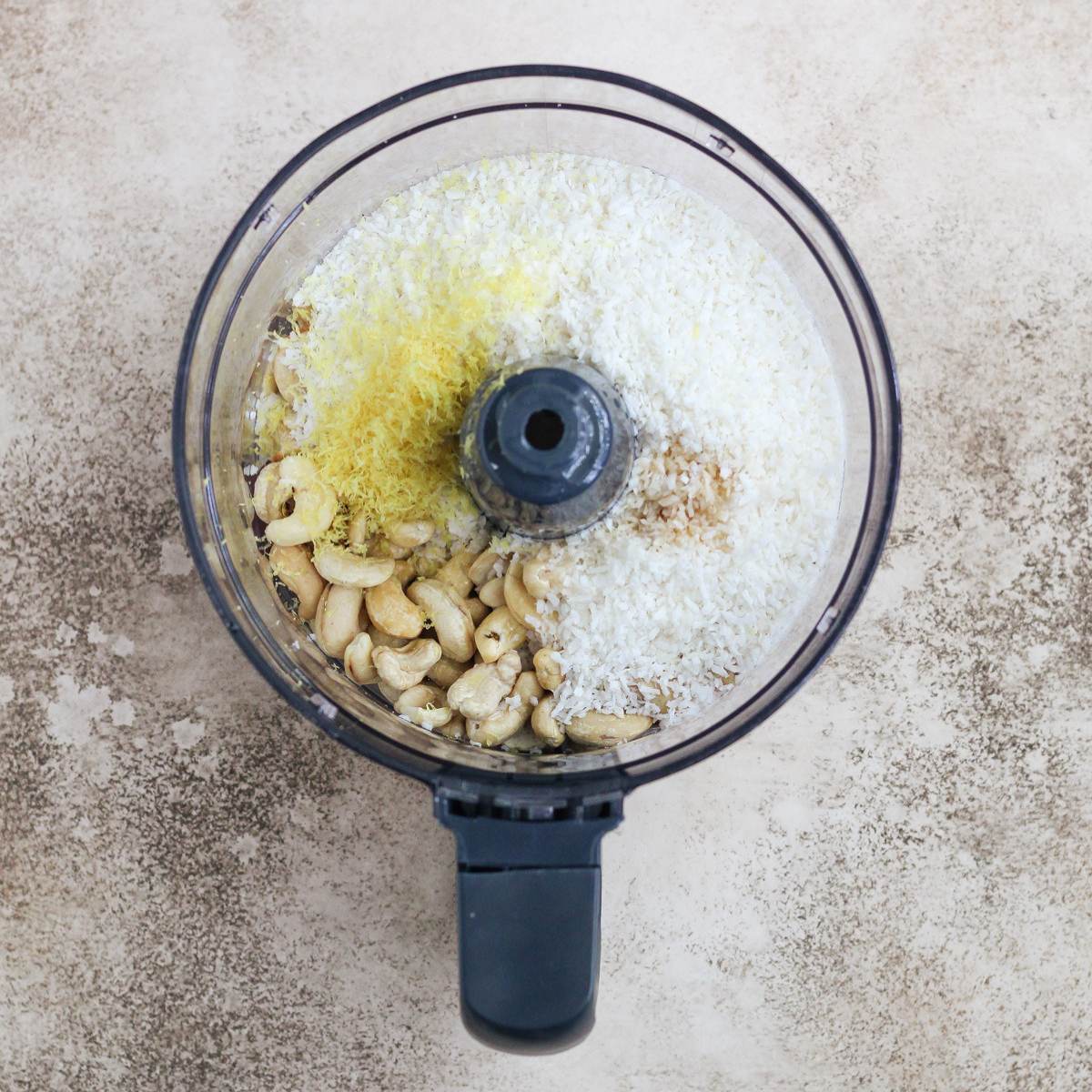 A food processor filled with the ingredients for lemon coconut date balls.