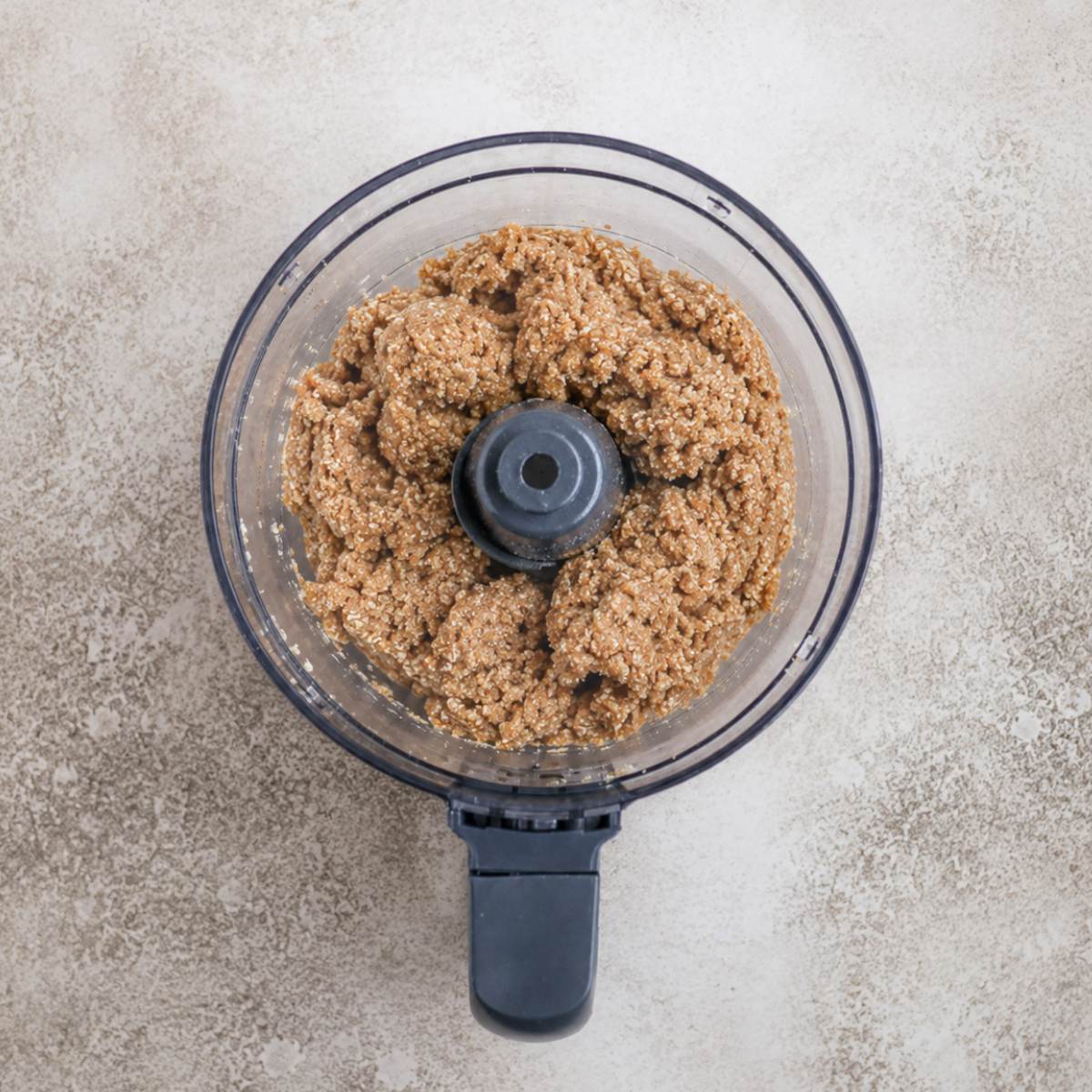 A food processor filled lemon coconut date ball ingredients blended together.