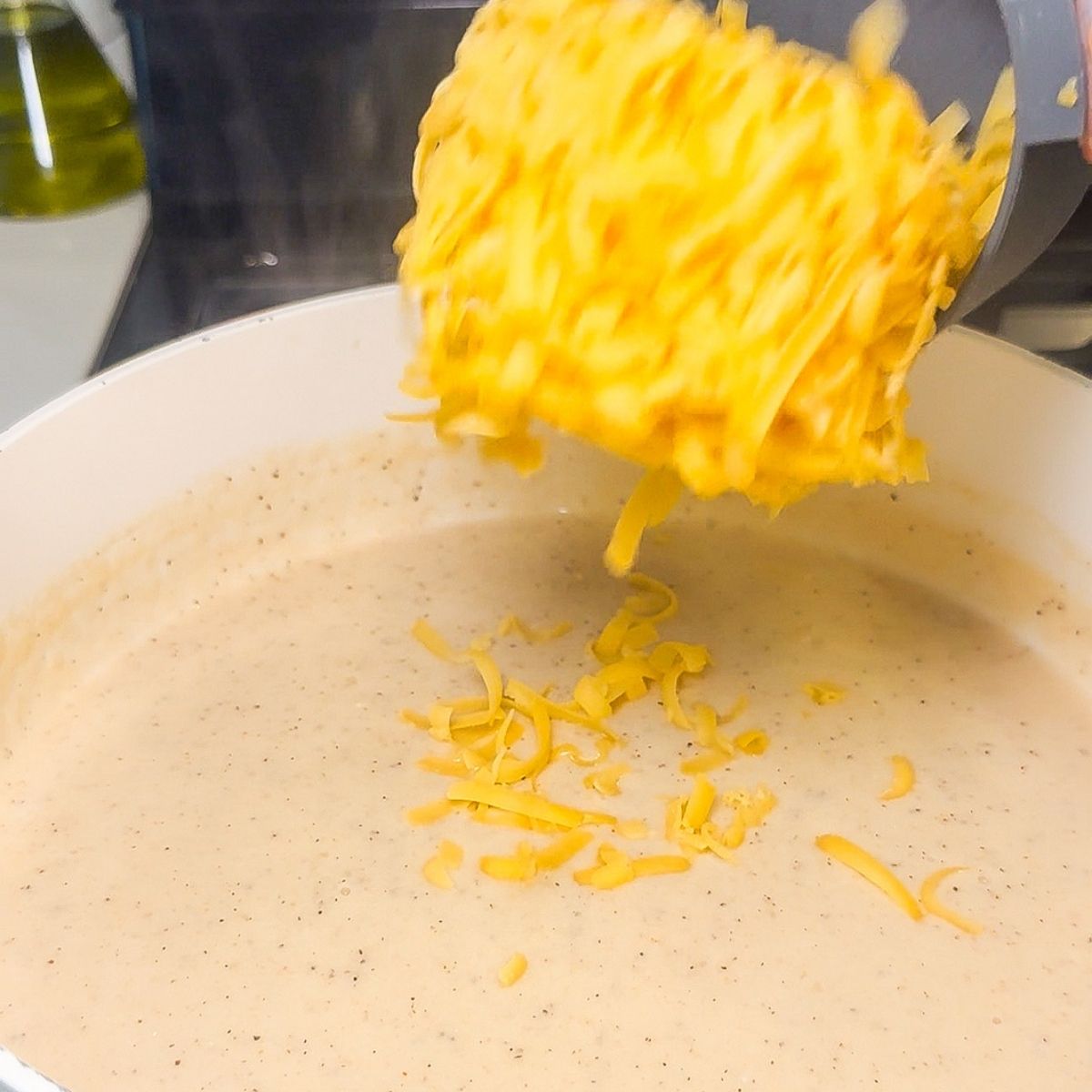 Cheese being poured into cottage cheese sauce.